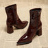 Brown glossy ankle boots showing side zippers and pointed toes