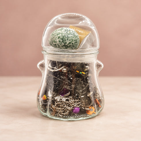 Clear jar filled with a mixed Halloween jewelry assortment in black, orange, and purple.