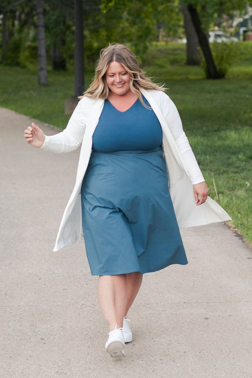 White long cardigan worn over a blue dress outdoors