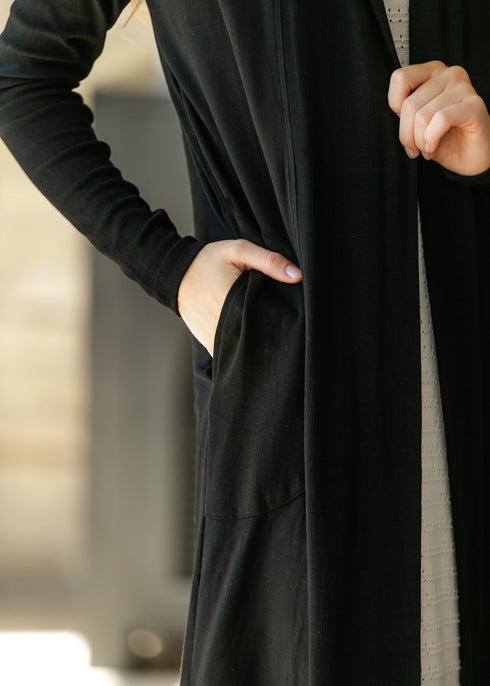 Close-up of a hand in the black cardigan pocket
