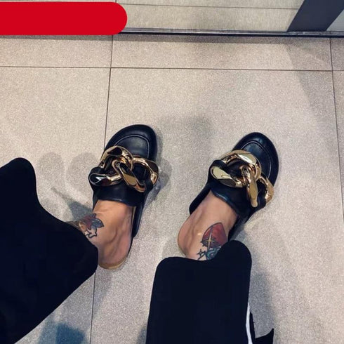 Black STEVVEX chain-detail mule flats worn with black pants, viewed from above