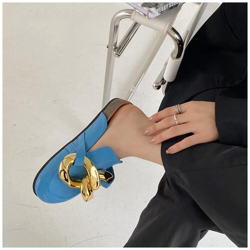 Blue chain mule held by hand showing the microfiber upper and open heel