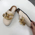 Beige chain mule flats held up to show top and side views