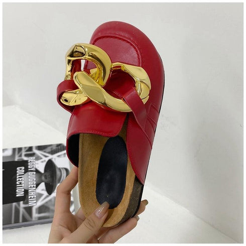 Red chain mule held up for a close view of the rounded toe and gold-tone links