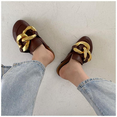 Brown chain mule flats worn with blue jeans, viewed from above