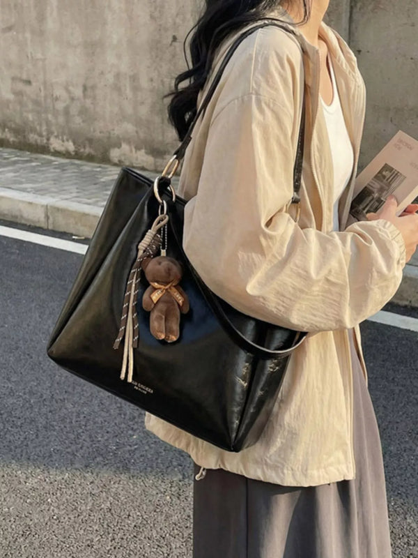 PU-Leather Shoulder Bag: Black tote with teddy bear charm worn, side view