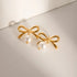 Gold-Tone Bow Earrings with Synthetic Pearls: Gold-tone bow earrings with white bead drops, angled flat lay