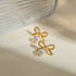 Gold-Tone Bow Earrings with Synthetic Pearls: Gold-tone bow earrings with white bead drops beside a glass vase