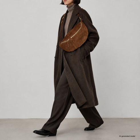 Brown Genova crossbody bag shown on a model with tailored clothing