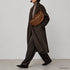 Brown Genova crossbody bag shown on a model with tailored clothing