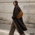 Brown Genova bag styled across the body on a model outdoors