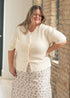 Ivory Zadie cardigan worn with a light floral skirt and hands at the waist